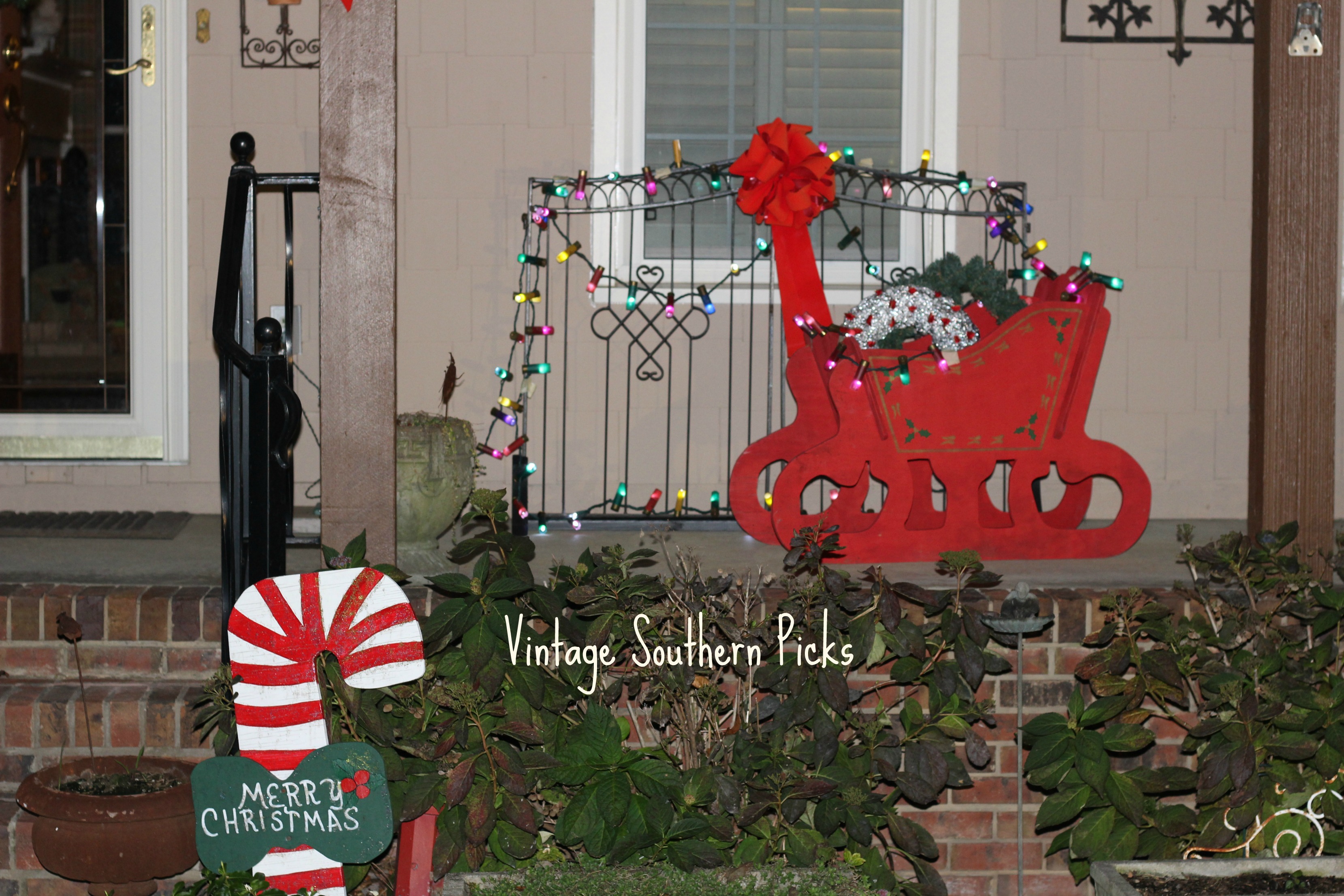 christmas-garland-lit-up-against-metal-gate
